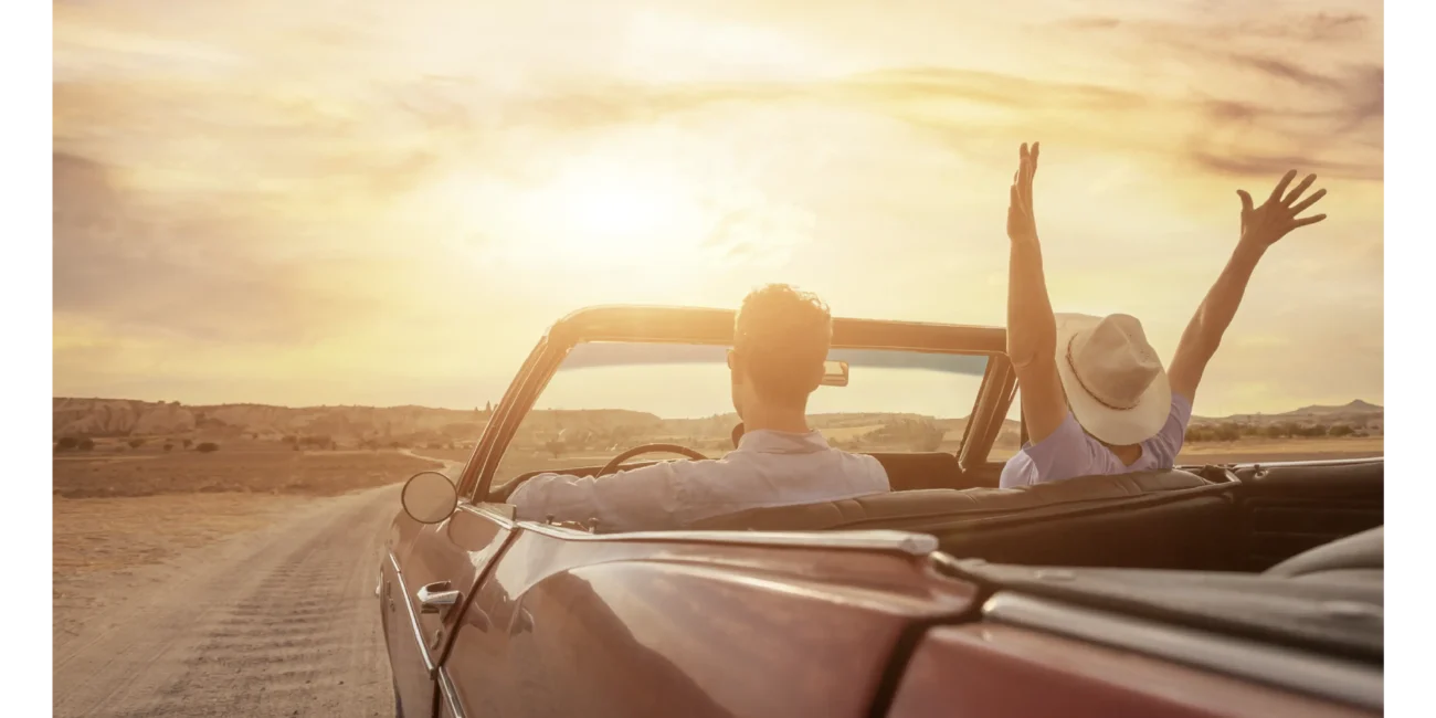 Pareja viajando en un carro antiguo rojo por un desierto. Lovit Matchmaking